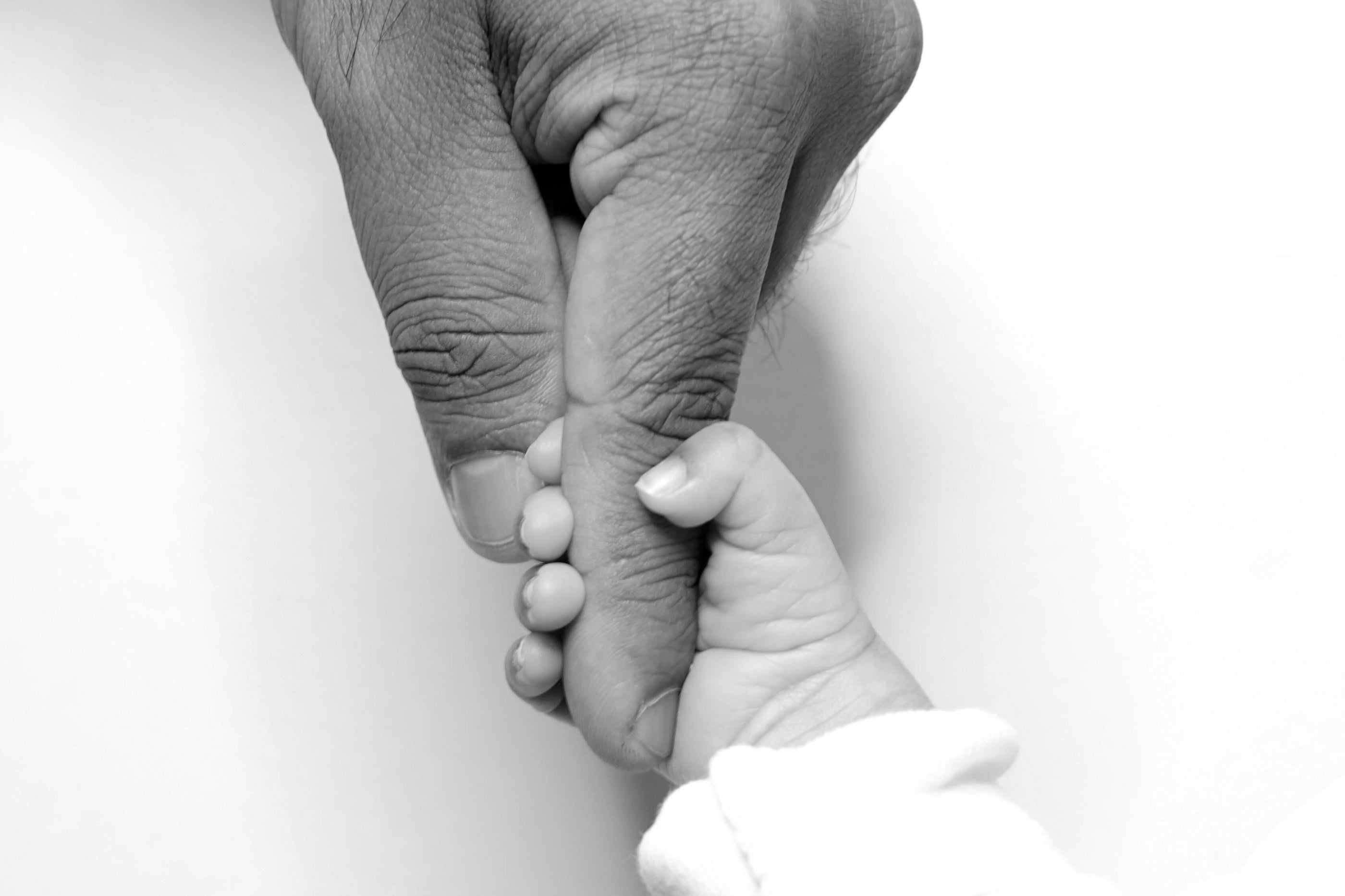 Black and white photo of an adult hand holding a child's hand